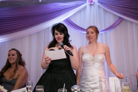 Three women at a wedding; one speaks while the others listen attentively.